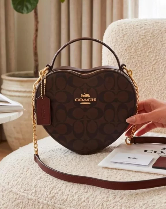 Stylish heart-shaped crossbody sling bag featuring elegant detailing, a top handle, and a long adjustable strap. Comes with box packing and a brand-style dust cover.